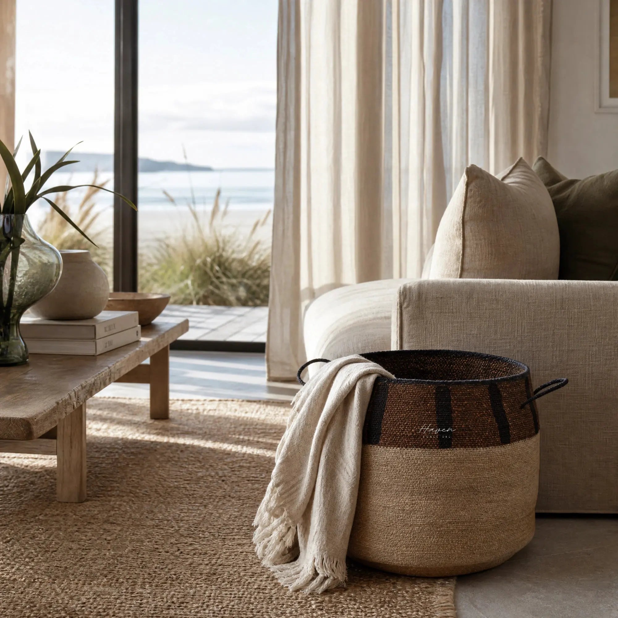 Aarna Basket: handwoven from seagrass with cream body, brown rim and chocolate stripes beside a sofa.