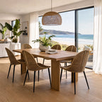 Celeste Dining Chair with natural woven rattan and slim black metal legs at a coastal dining table.