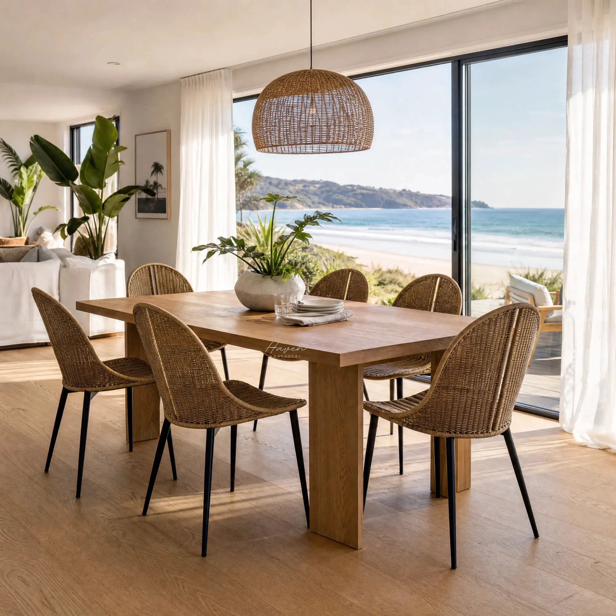 Celeste Dining Chair with natural woven rattan and slim black metal legs at a coastal dining table.