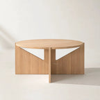 Kristina Dam Simple Table in FSC oak with a round top and sculptural vertical supports featuring white panels.