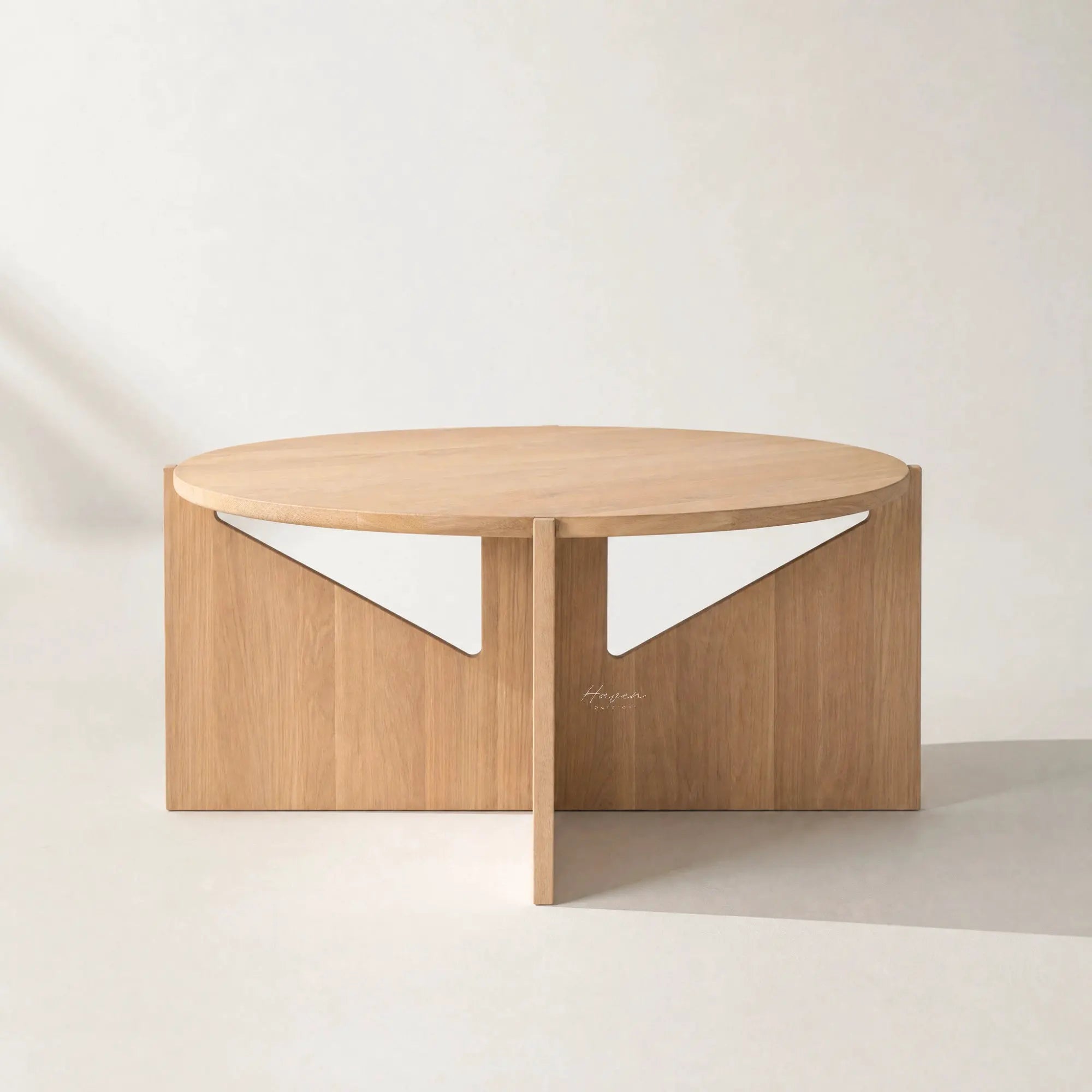 Kristina Dam Simple Table in FSC oak with a round top and sculptural vertical supports featuring white panels.