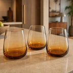 Broste Tumbler Set/8 Amber—mouthblown glasses with warm amber base on a dining table.