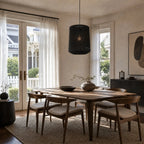 Ren Lampshade - Black woven pendant light over a wooden dining table in a bright room.