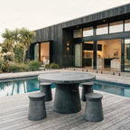Broste Outdoor Dining Table on a modern deck with sculptural fiberclay pedestal bases, concrete-like finish.