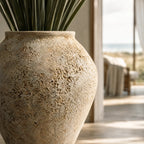 MUUBS Pot Trace 55 in coral/sand with rough porous terracotta surface and green leaves.