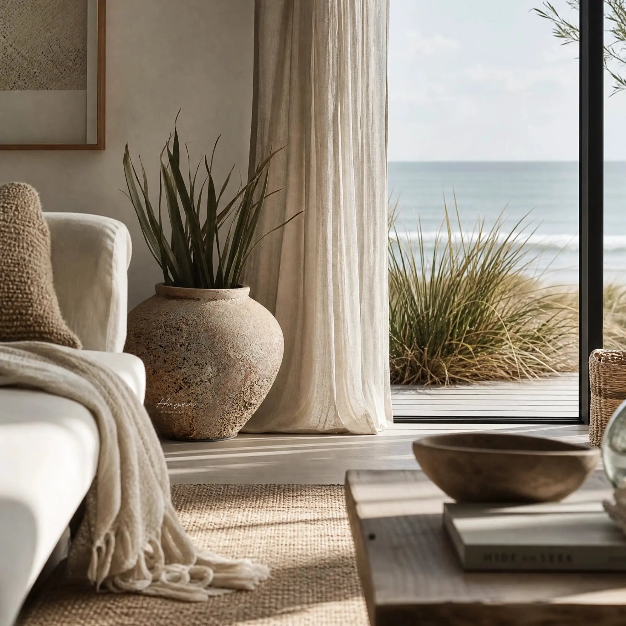 MUUBS Pot Trace 30 coral/sand terracotta planter with tall plant by a window overlooking the sea.