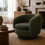 Monika Swivel Chair in dark green fabric with a soft sculptural silhouette, curved back, and swivel base.