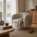 Monika Swivel Chair - Latte with soft curved back and cozy throw in a sunlit living room.