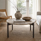 Sigrid Coffee Table with a round dark travertine-like GRC top and chocolate-brown metal legs in a sunlit living room