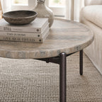 Sigrid coffee table with a round, dark travertine-like stone top on a chocolate brown metal frame.