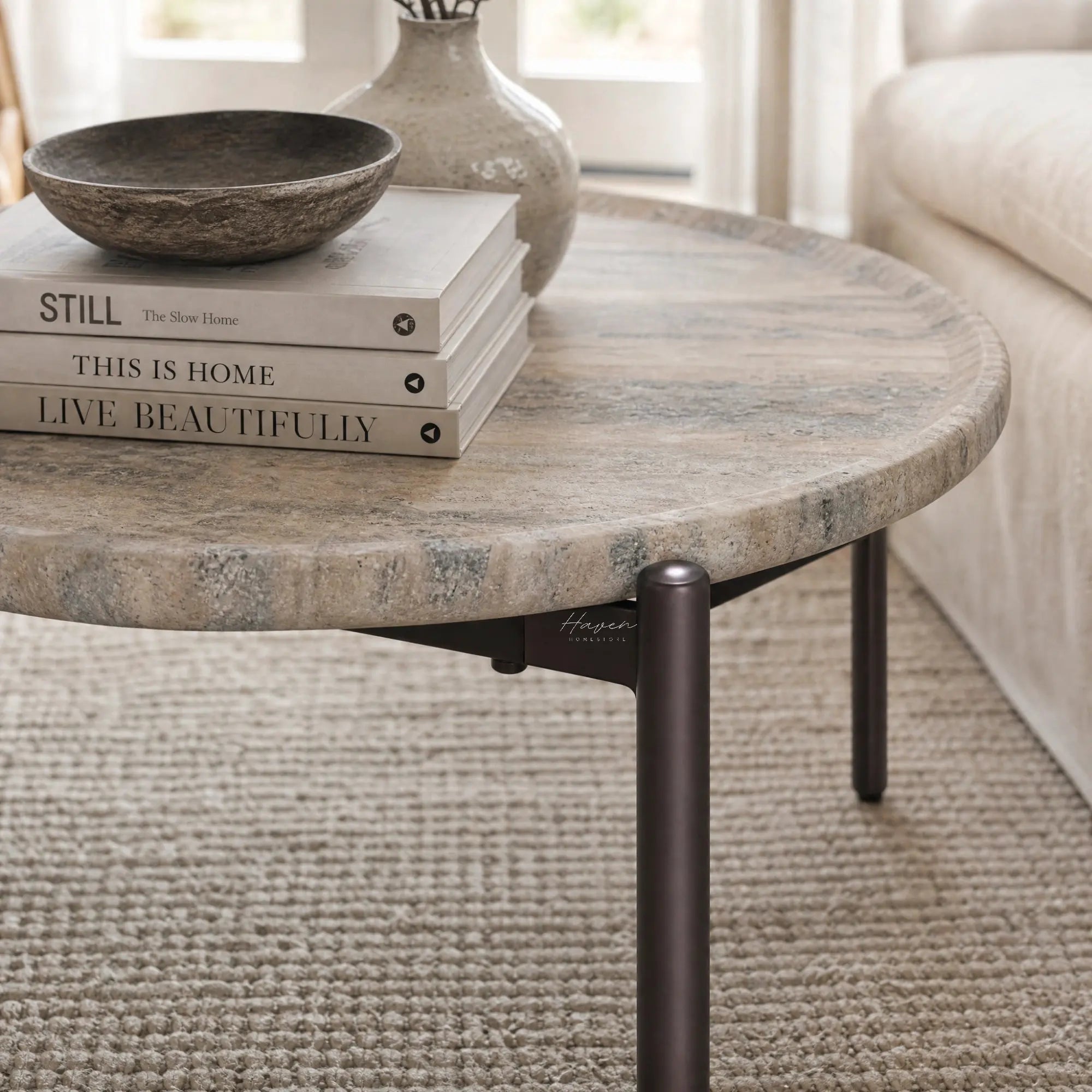 Sigrid coffee table with a round, dark travertine-like stone top on a chocolate brown metal frame.