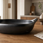 La Chamba baking dish, hand-moulded from naturally dark grey clay, oven-to-table cookware in a warm kitchen.