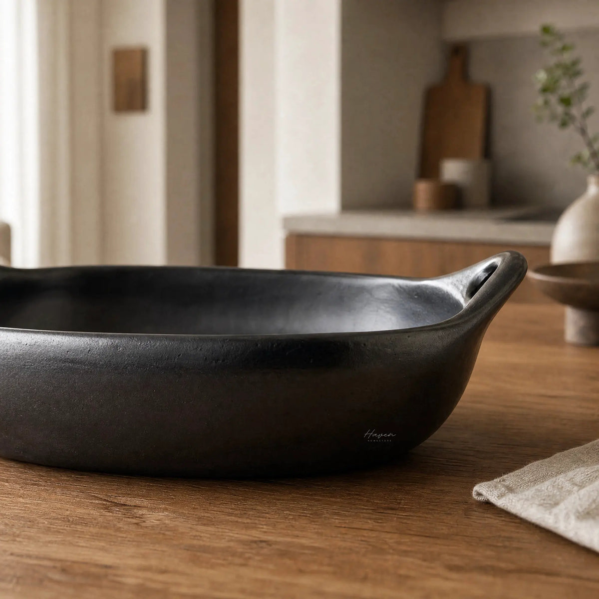 La Chamba baking dish, hand-moulded from naturally dark grey clay, oven-to-table cookware in a warm kitchen.