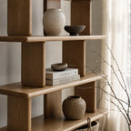 Jansen Shelving Unit in natural timber with open shelves for books and ceramic vessels.