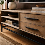 Atlas Entertainment Unit in natural oak with metal detailing, open shelves and drawers, styled with books and bowls.