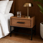 Atlas Bedside Table in solid oak with powder-coated metal frame, a drawer, brass lamp, and a glass of water.