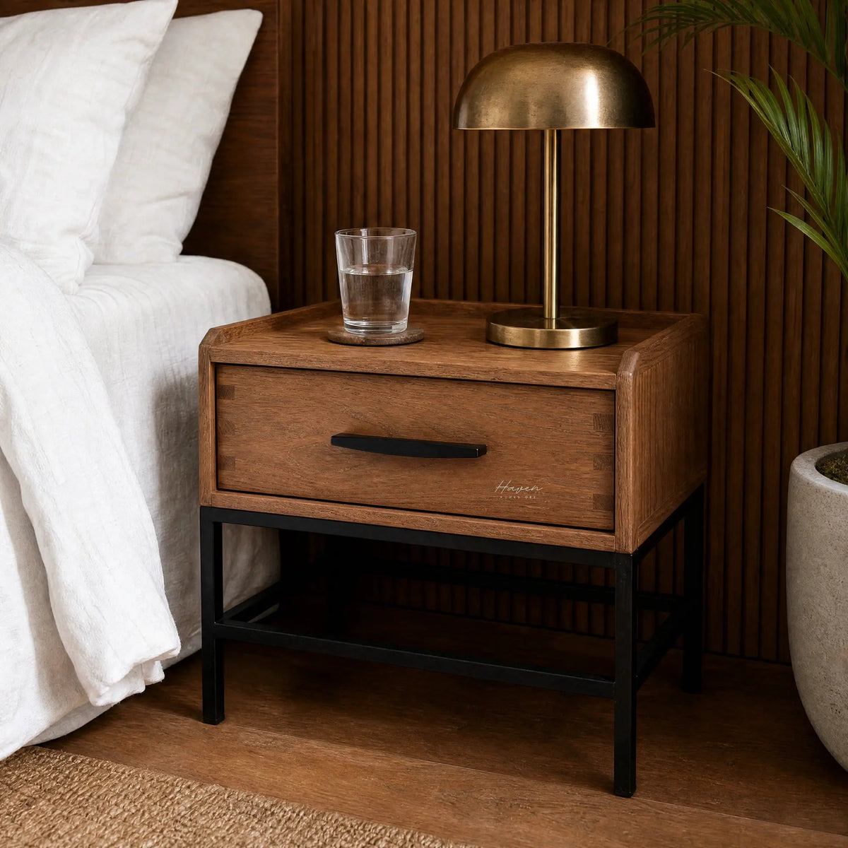 Atlas Bedside Table in solid oak with powder-coated metal frame, a drawer, brass lamp, and a glass of water.