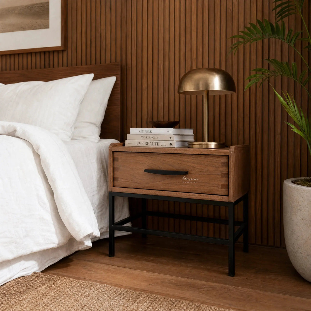 Atlas Bedside Table in solid oak with a black powder-coated metal frame and a generous drawer beside a bed.