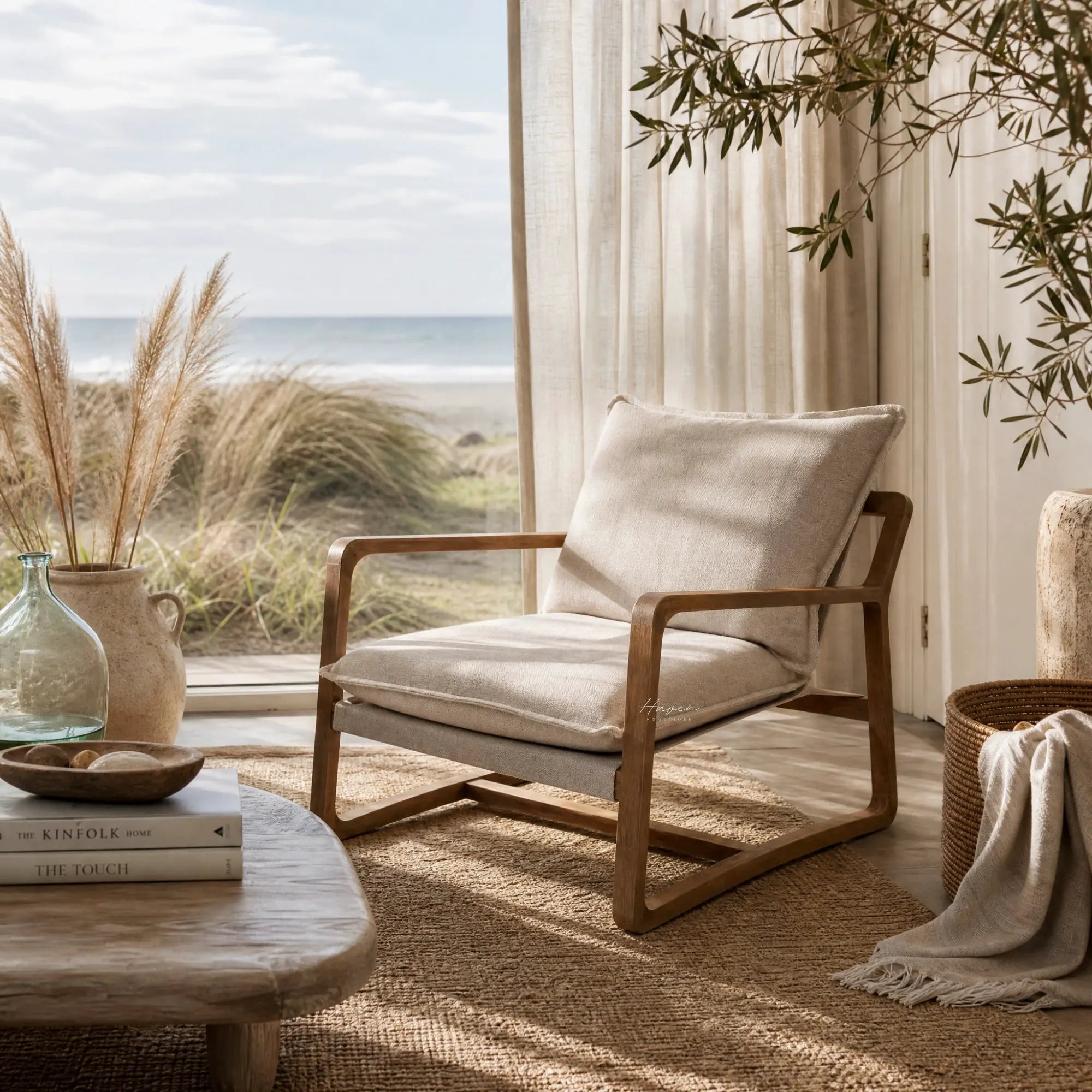 Tide Lounge Chair in Sand with solid oak frame and stone-washed cotton cushions beside a sunlit coastal window.