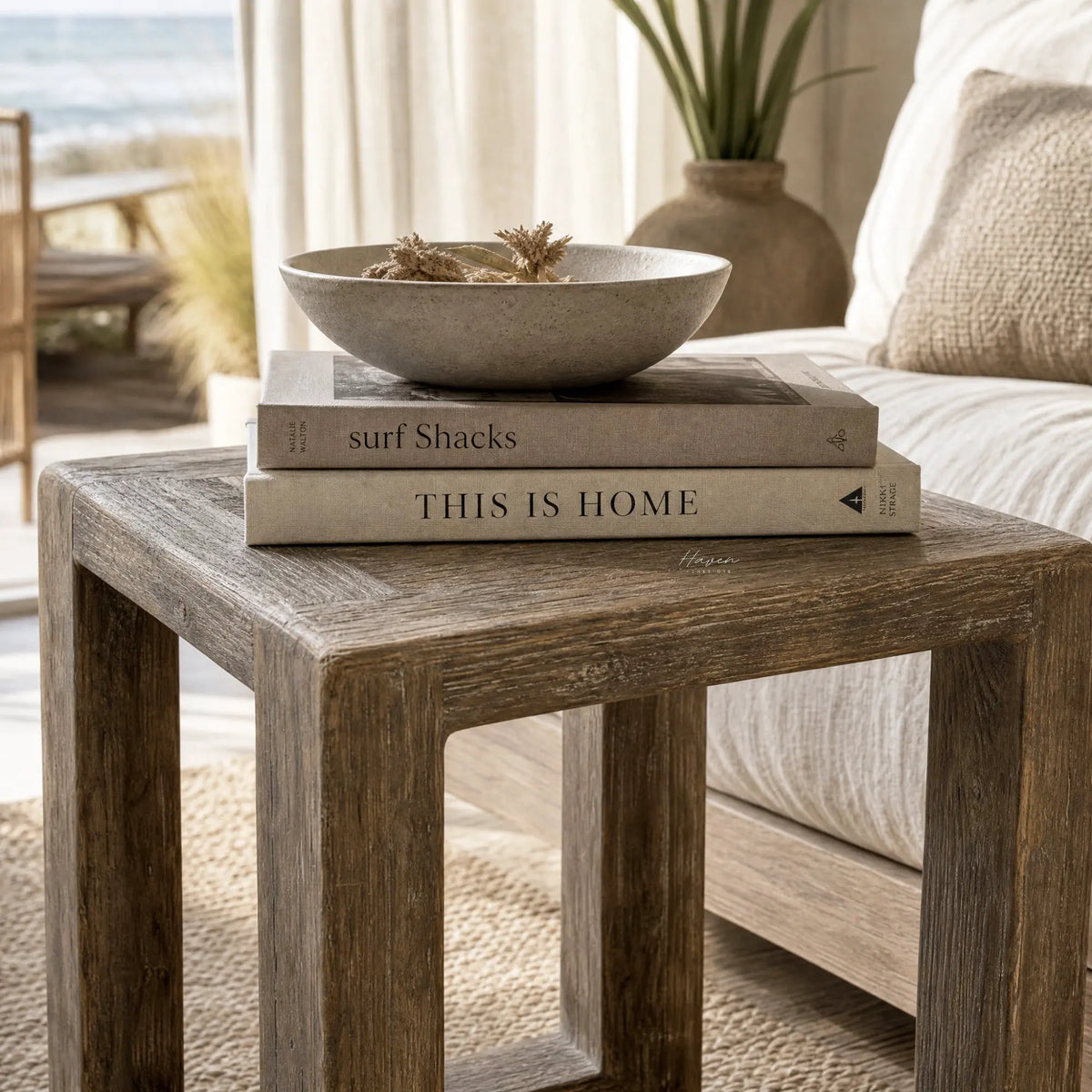 Estuary Side Table with textured reclaimed elm, topped by a bowl and books in a coastal living room.