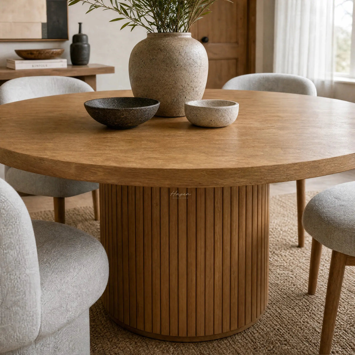 Linden Dining Table with a 140cm round solid wood top, warm finish, surrounded by grey upholstered chairs.