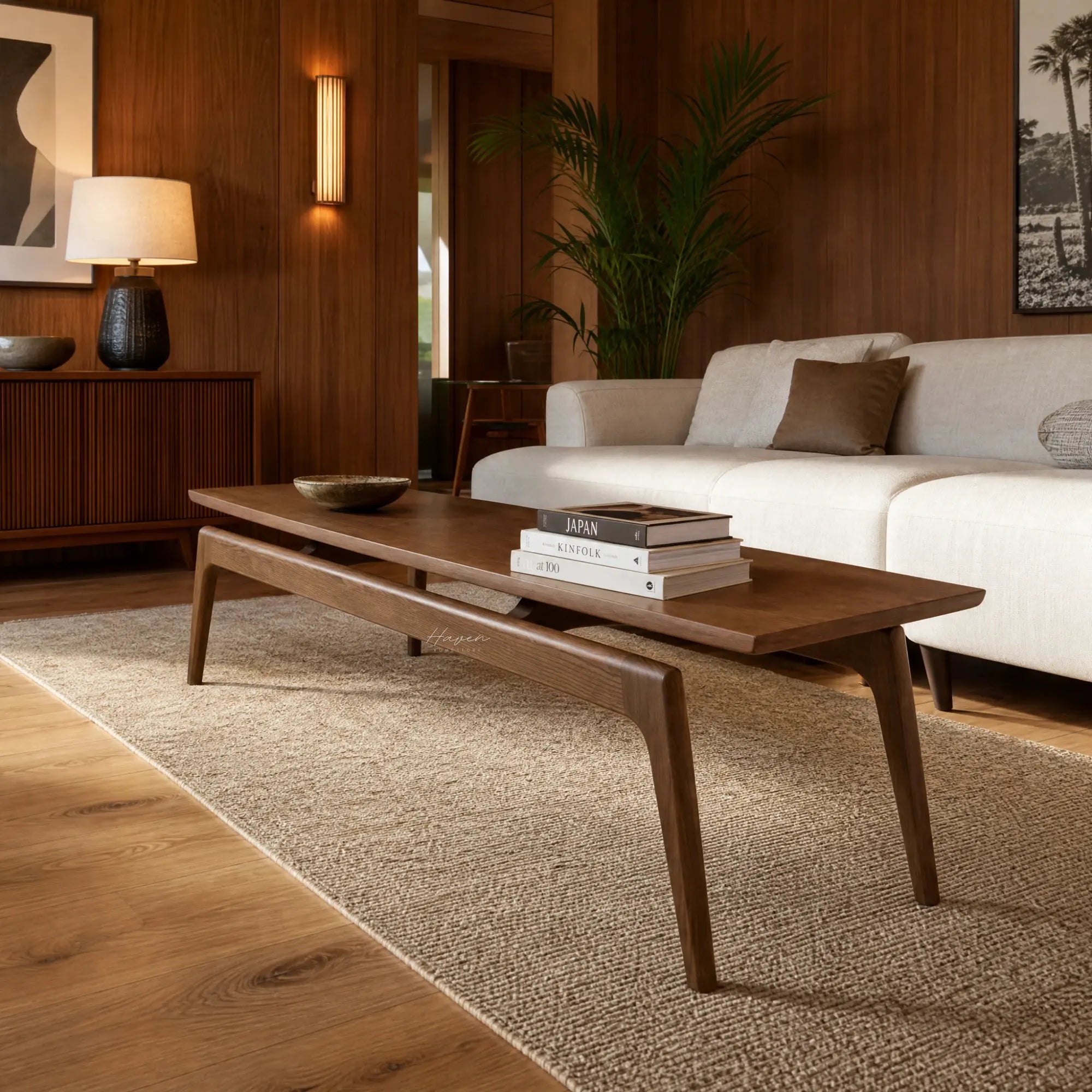 Rowan Coffee Table in solid American Ash with mid-century lines, shown with stacked books in a warm living room.