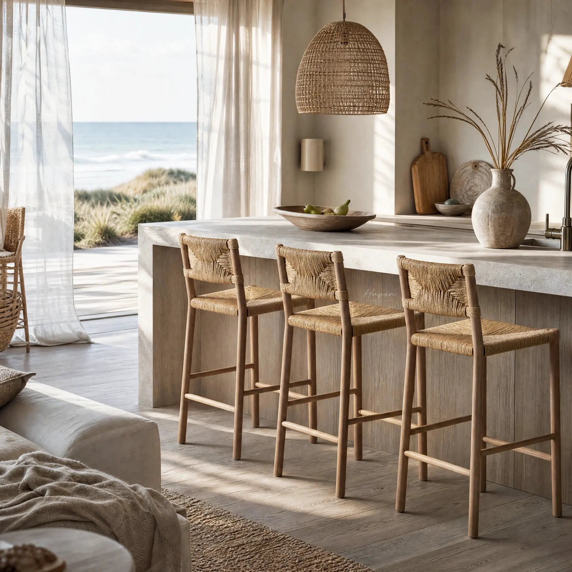 Drift Counter Stool with solid oak frame and handwoven seagrass seat and backrest at a coastal kitchen island.