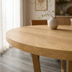 Ashburton Dining Table in warm oak with a round top and architectural base, in a bright NZ dining room.