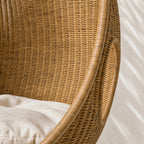 Rattan Pod Chair handwoven from natural rattan with cocoon-like shape and beige cushion.