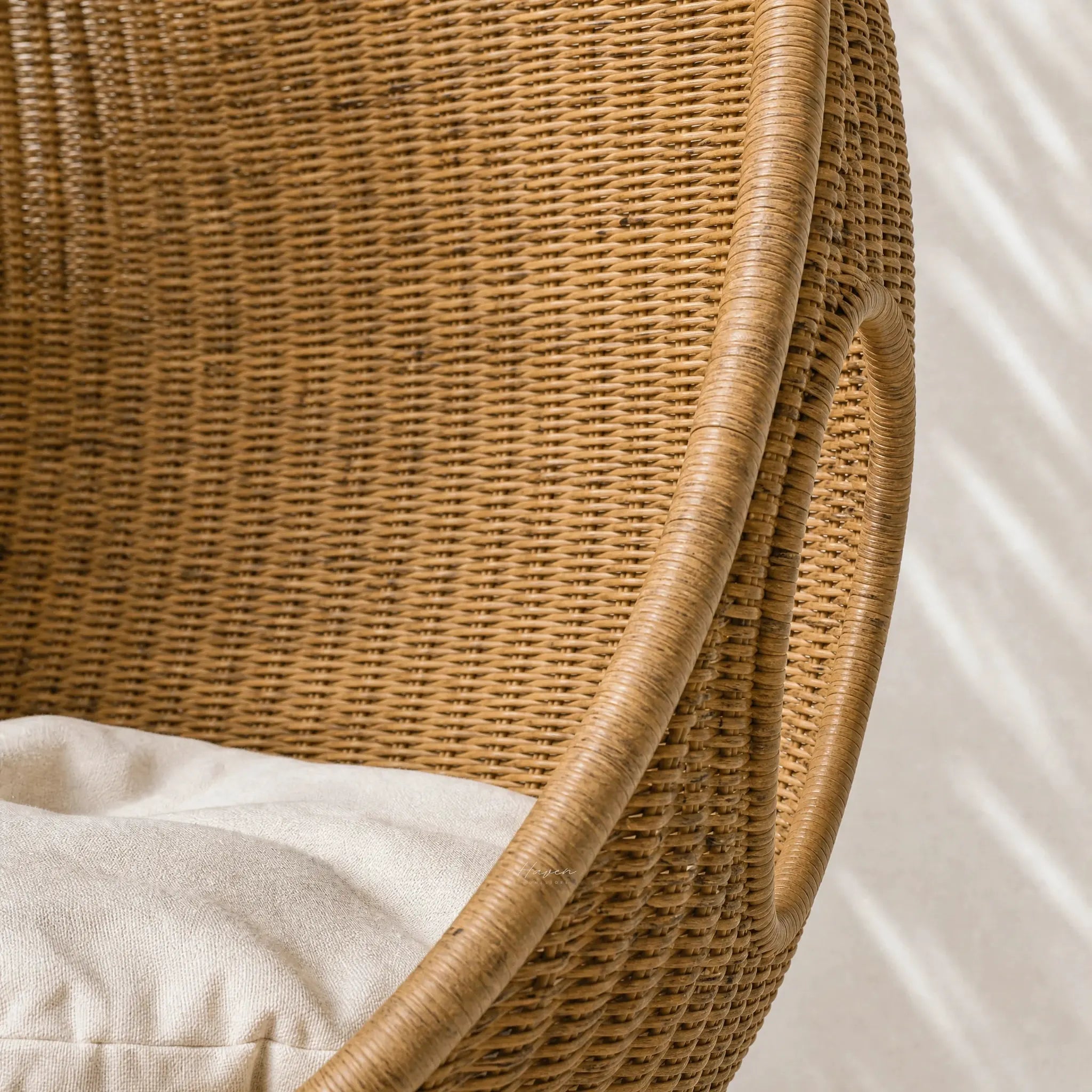 Rattan Pod Chair handwoven from natural rattan with cocoon-like shape and beige cushion.