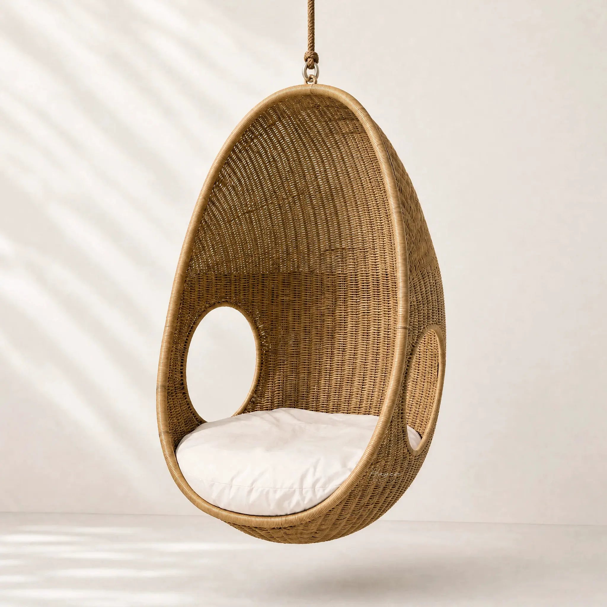 Rattan Pod Chair: hanging handwoven cocoon seat in natural rattan with white cushion.