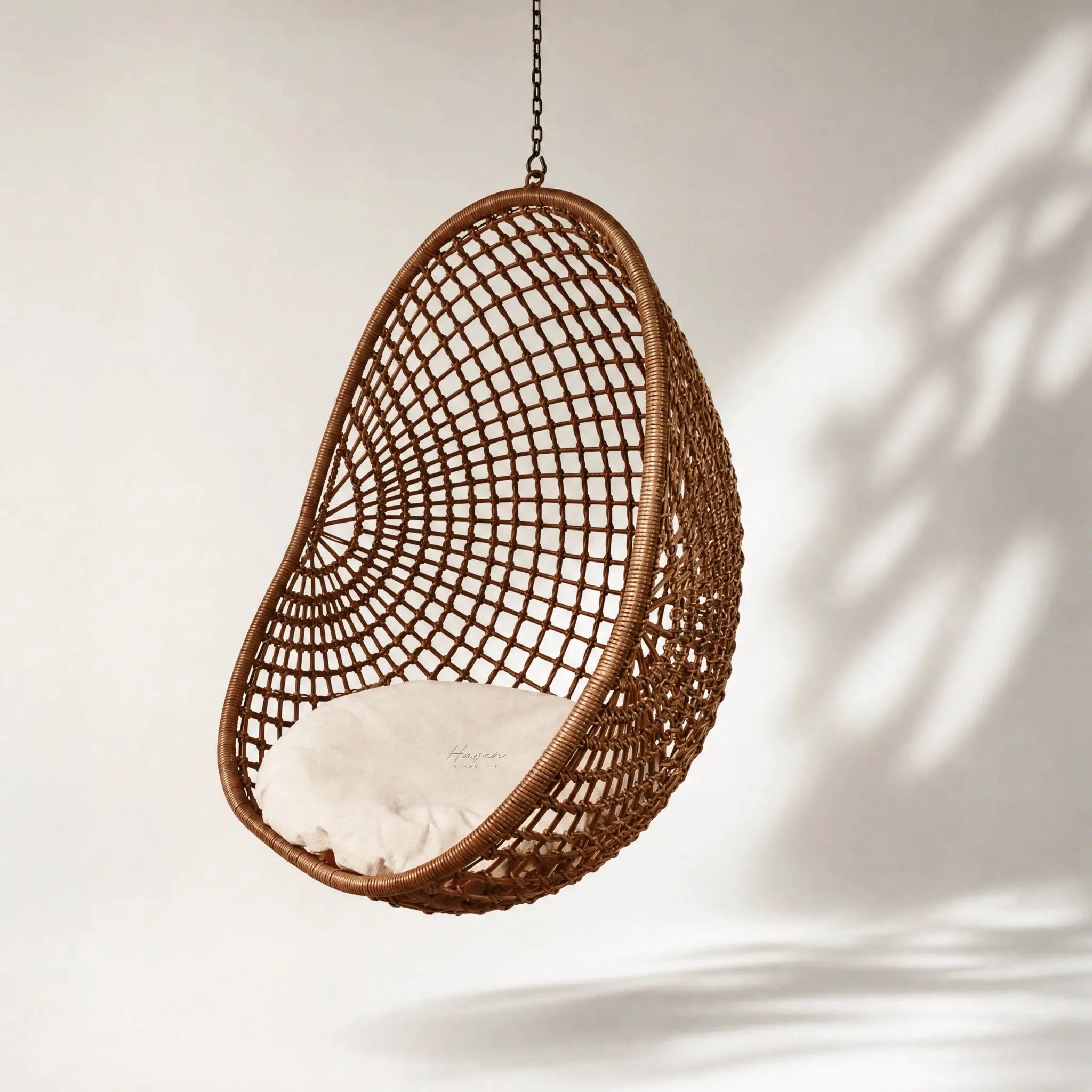 Check Pod Chair hanging wicker pod with lattice weave and beige cushion.