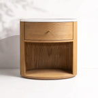 Dana Bedside Table in oak with white marble top, rounded silhouette, single drawer and open shelf.