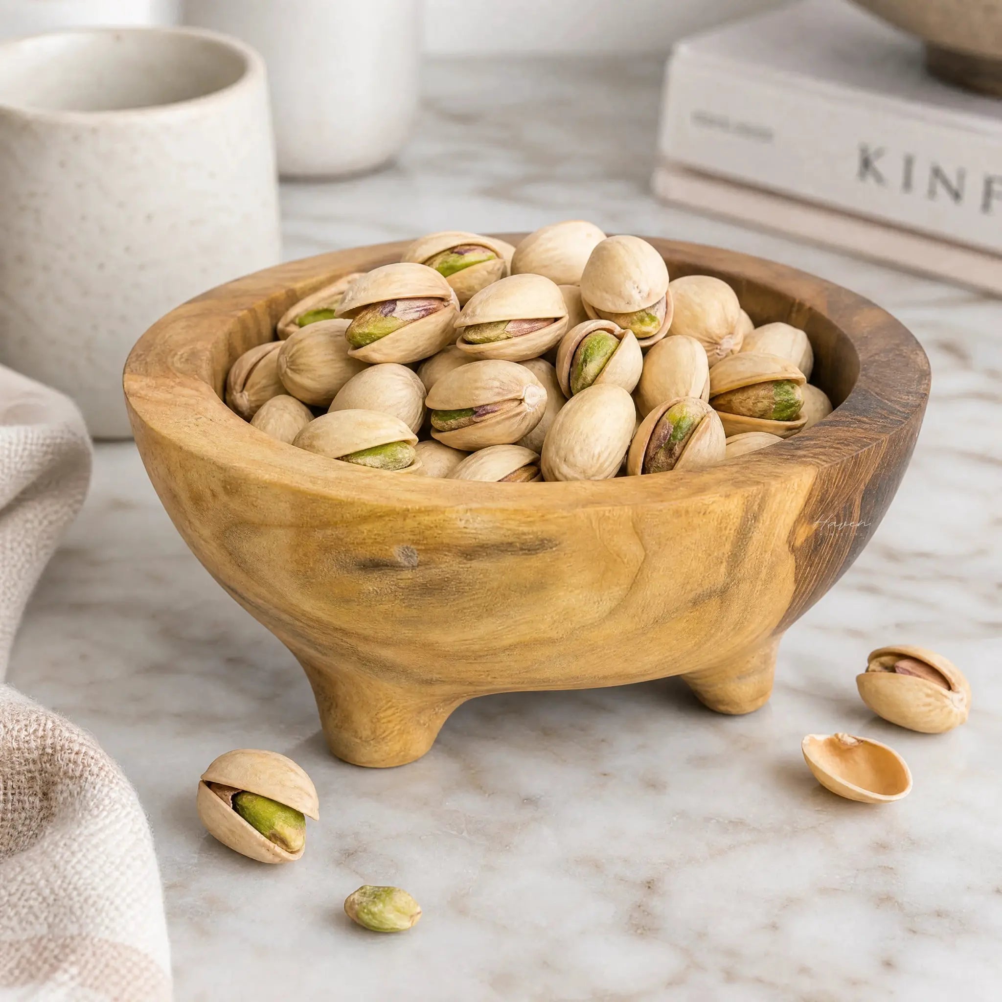 Teak Bowl Set/2 with pistachios in a hand-carved teak bowl on a marble surface.
