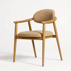Celine Dining Chair with warm ash wood frame and rounded beige upholstered seat and backrest.