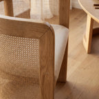 Cove Cane Chair: curved oak frame with woven rattan panels and a softly cushioned seat.