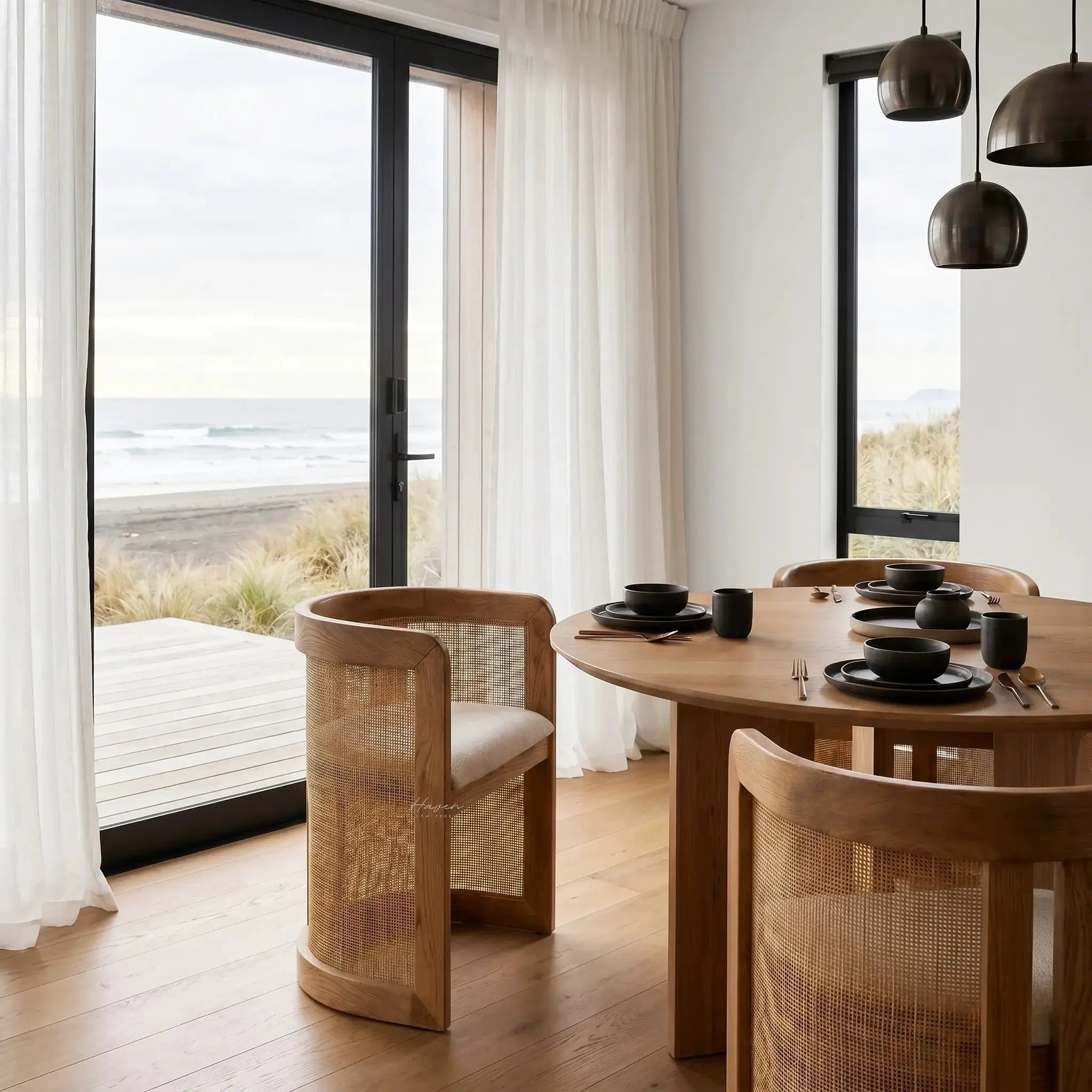 Cove Cane Chairs with curved oak frames, woven rattan panels, and softly cushioned seats around a round dining table.