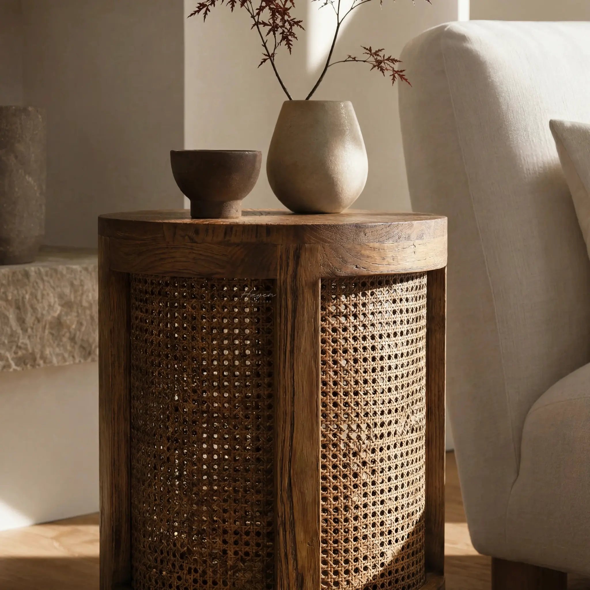 Cala Side Table in elm with natural rattan panels, featuring dark cup and pale vase with branches.