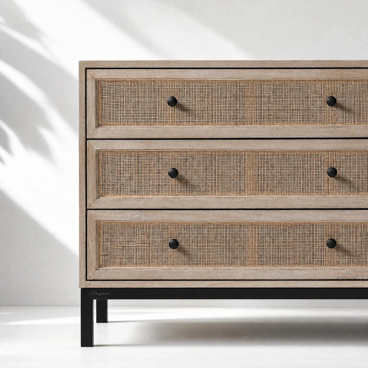 Cadrona 3 Drawer Commode with woven rattan fronts, timber frame, and slim black iron base.