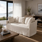 Cove 2-seat slipcovered sofa in cream linen-cotton with plush cushions in a seaside living room.