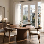 Sora Dining Table - Walnut with a round top and fluted pedestal, set in a sunlit dining room.