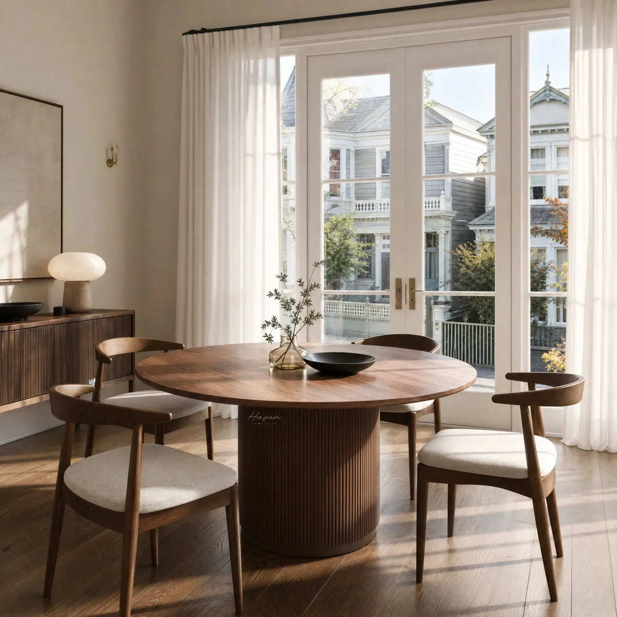 Sora Dining Table - Walnut with a round top and fluted pedestal, set in a sunlit dining room.