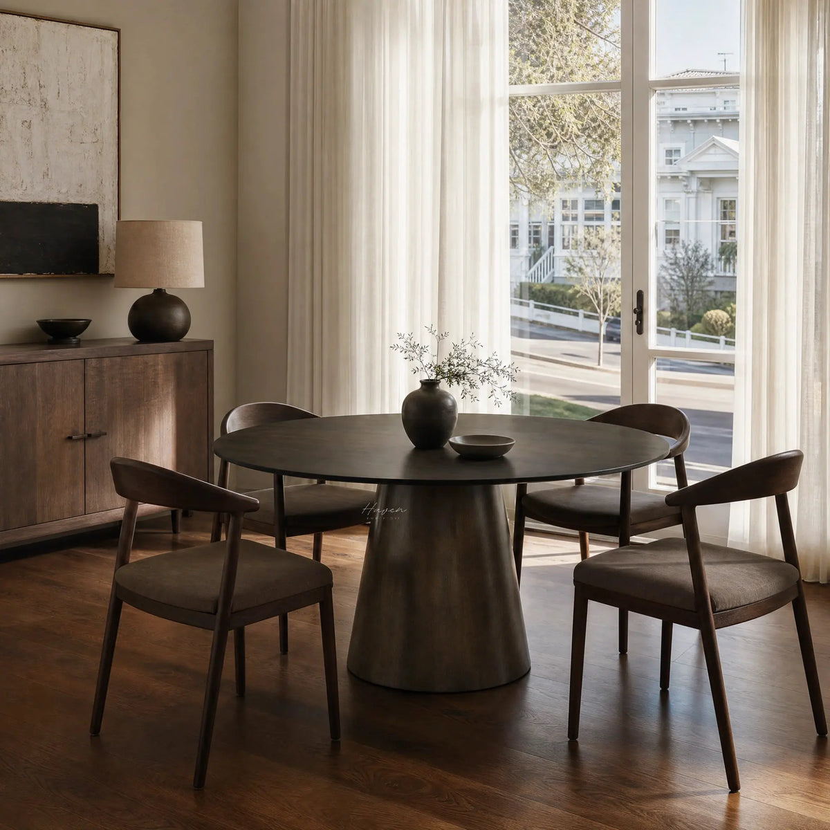 Mika Dining Table in warm mango wood with round top and tapered pedestal in a Japandi dining room.