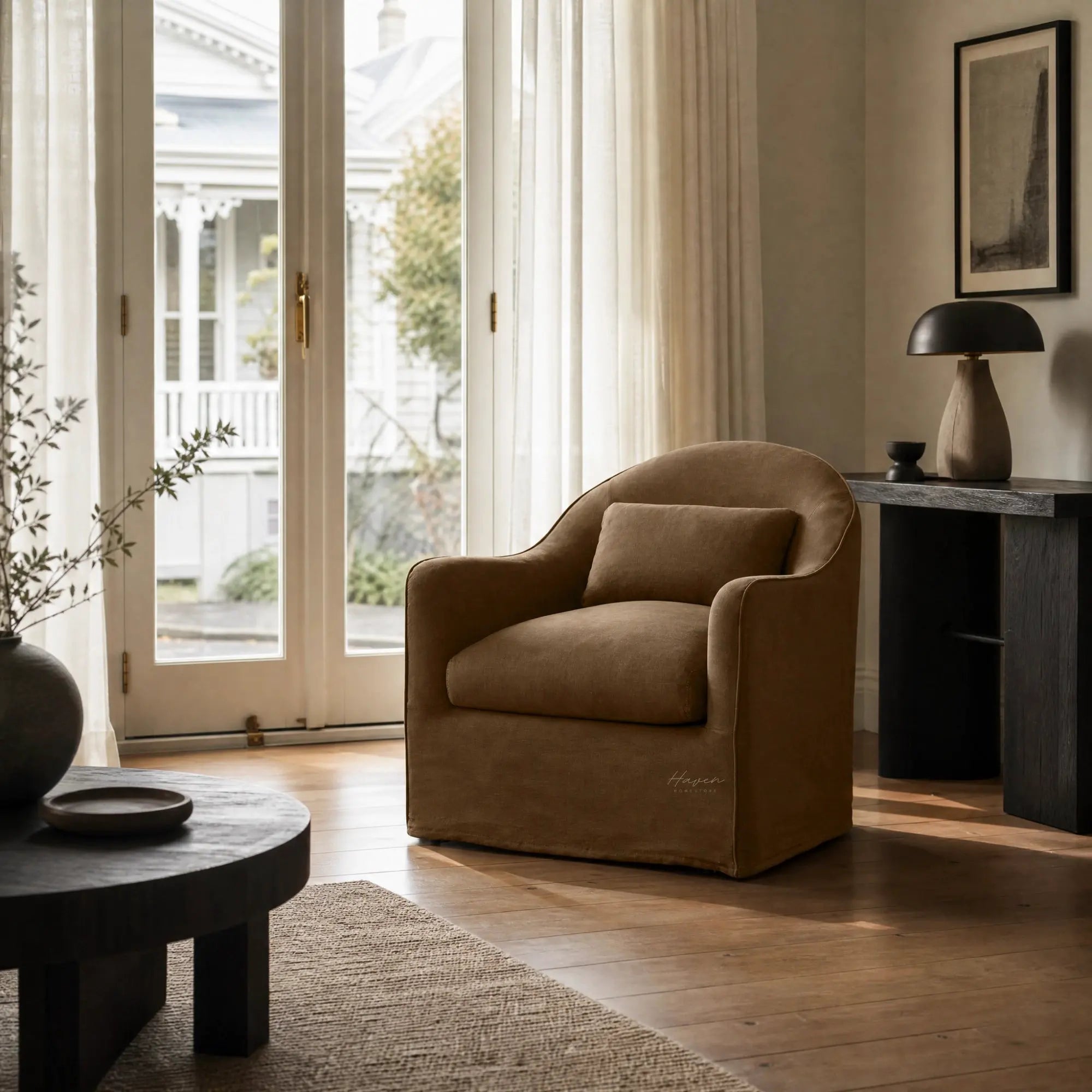 Nella slipcover armchair in warm Mocha linen features a softly curved silhouette and relaxed removable cover in a sunlit living room.