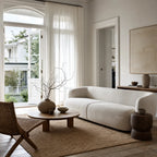 Low profile Luno sofa with a continuous curved back and pale textured upholstery bringing architectural calm to a serene living room.