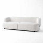 Low profile sofa with continuous curved back and pale textured upholstery bringing architectural calm to the room.