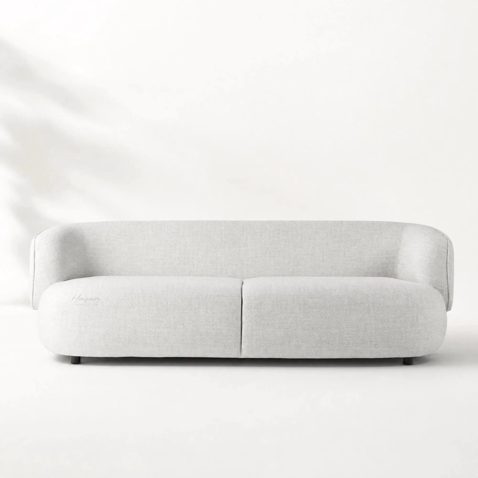 Low profile sofa with a continuous curved back and pale textured upholstery bringing architectural calm to the room.