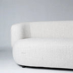 Low profile sofa with softly rounded back and pale textured upholstery creating architectural calm.