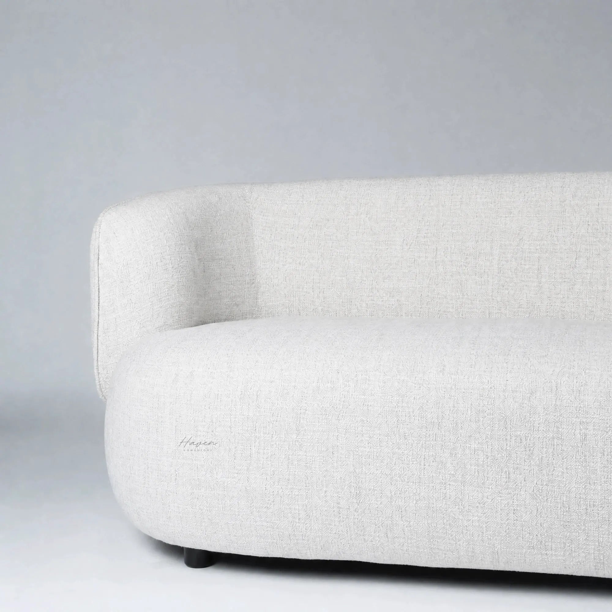 Low profile sofa with softly rounded back and pale textured upholstery creating architectural calm.