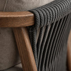 Dark rope detailing on the curved walnut wood armrest and grey upholstery of the Kiso lounge chair.